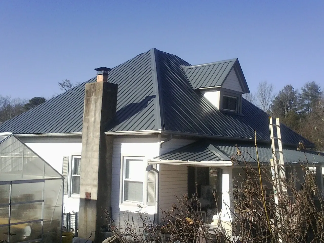 Dark blue standing seam metal roof on a white farmhouse with dormer — Slate & Tile Roof Repair by Roofing Brothers in Wayland
