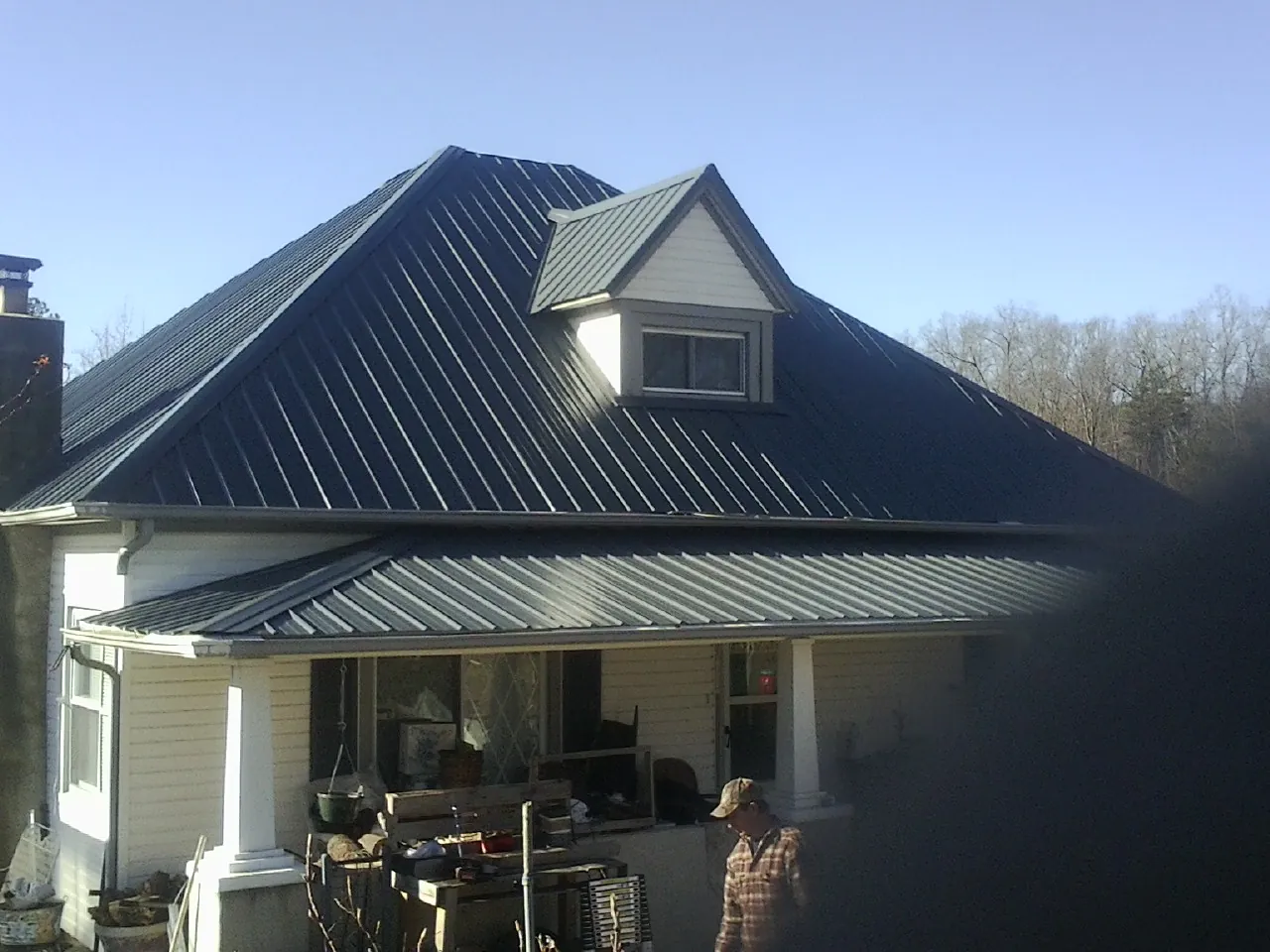 Dark blue standing seam metal roof with a dormer above a front porch in Wayland